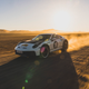 A Porsche 911 Dakar speeds across the desert with a Rallye 1971 livery